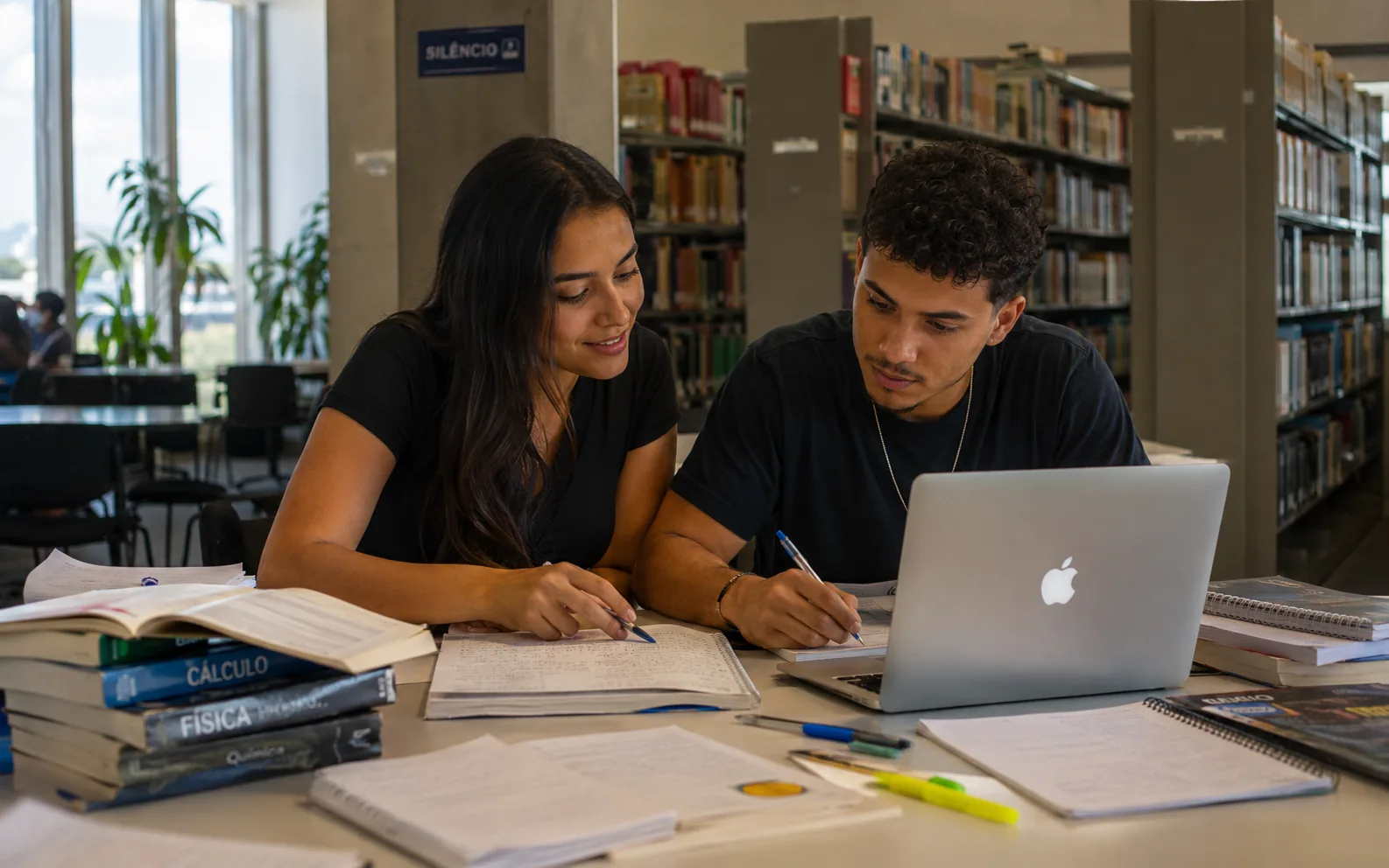 Dupla de estudantes revisando conteúdo básico na biblioteca